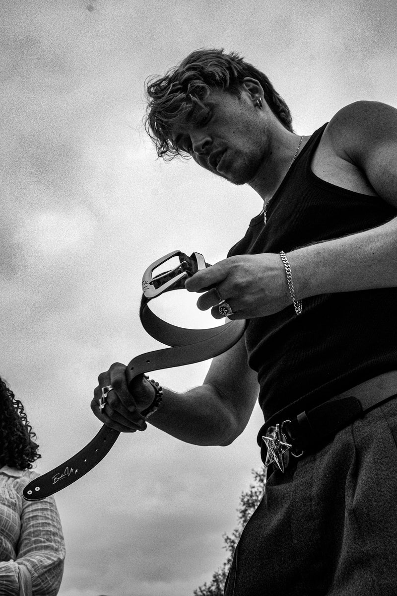 Close view of a model holding a YUP belt outdoors