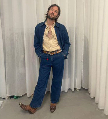 A person wearing a denim outfit with a cowhide belt.