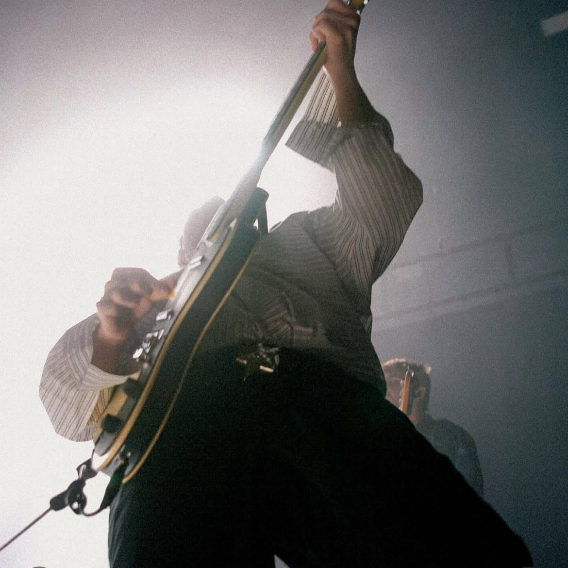 Person playing guitar wearing a star buckle leather belt with a blurred background