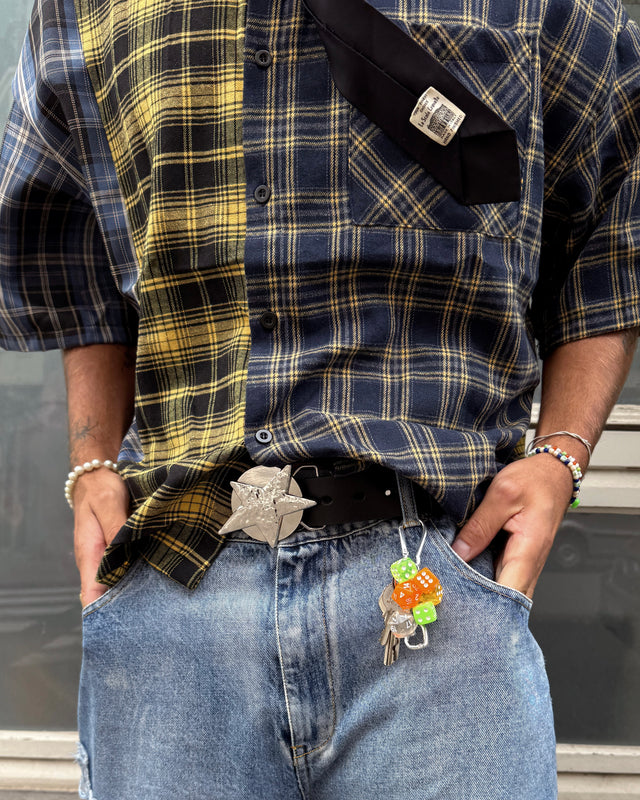Person wearing a plaid shirt and jeans with a leather belt that has a star buckle and keys hanging from it.